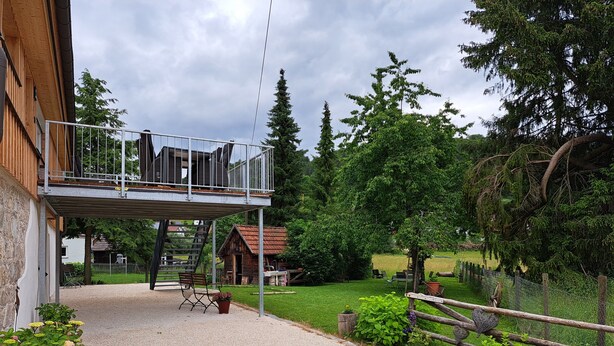 En byggnad med en balkong, en grusuppfart och en inhägnad trädgårdsyta.