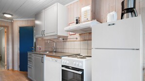 A modern kitchen with white cabinetry, a stove, a dishwasher, and a coffee maker. - First Camp Beitostølen - Valdres (Beitostølen)