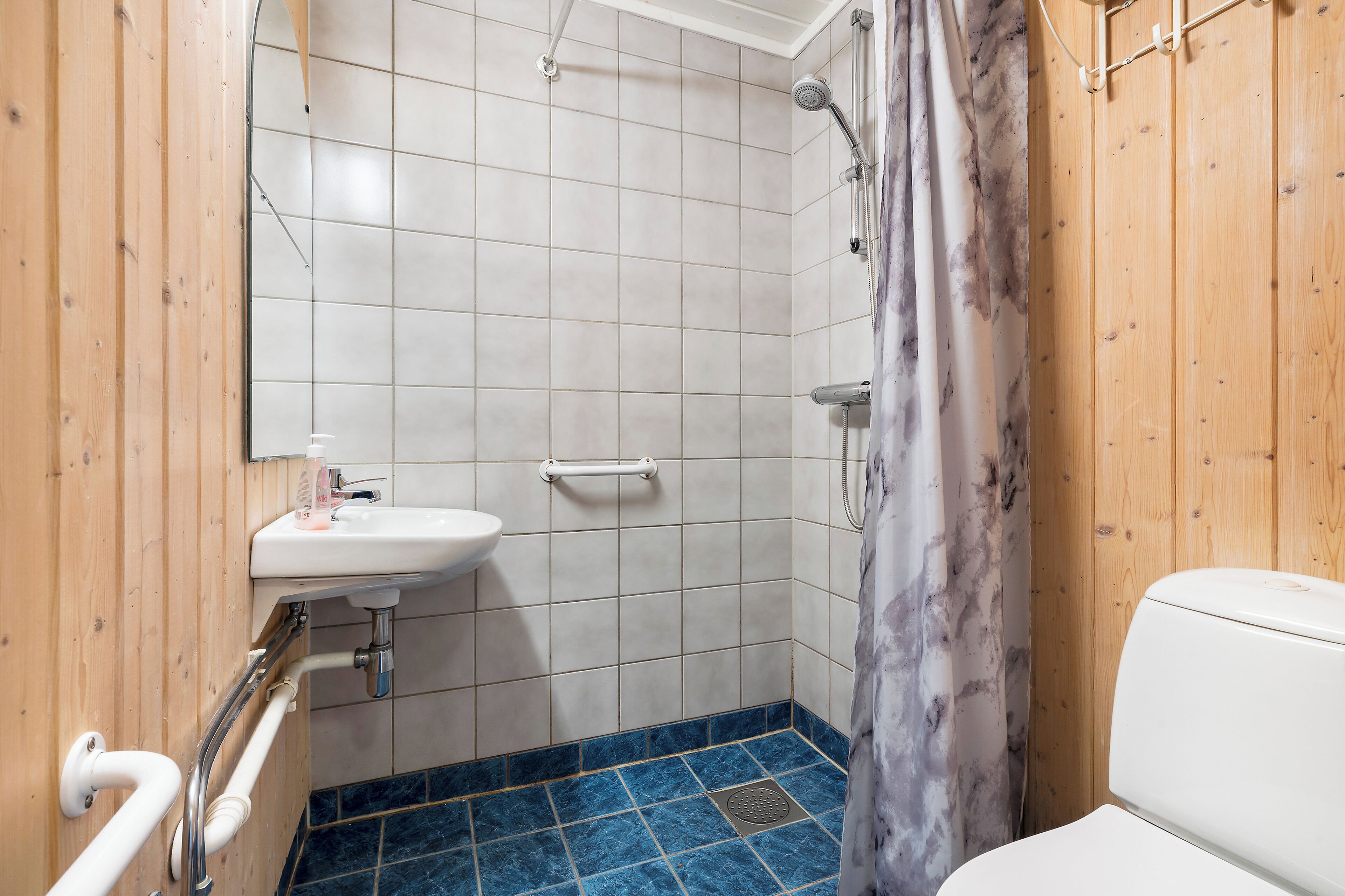 A bathroom with a white sink, a shower, and a toilet.
