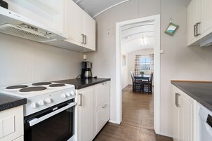 A modern kitchen with white cabinetry, a stove, and a coffee maker.