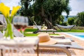 Un área junto a la piscina con sillones de descanso, una hamaca y vistas al paisaje.