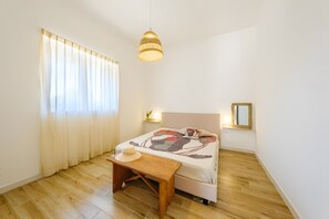 A bedroom with a bed, a wooden floor, a hanging light fixture, a bedside table, and a window with curtains. - Apartment 'Dream' with Private Terrace, Wi-Fi and Air Conditioning (Monopoli)