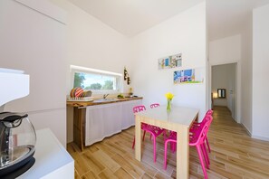 A modern kitchen with a window, a dining table with chairs, and a view of a hallway. - Apartment 'Dream' with Private Terrace, Wi-Fi and Air Conditioning (Monopoli)