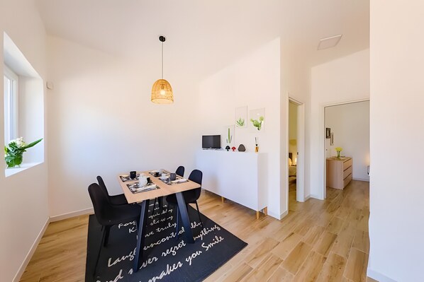 Een moderne eetruimte met een houten tafel, zwarte stoelen, een hanglamp en een zwart tapijt met witte tekst.