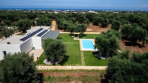 Zona residencial con piscina, paneles solares en un edificio y abundante vegetación.