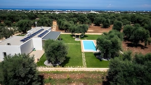A residential area with a swimming pool, solar panels on a building, and dense greenery. - Apartment 'Oasis' with Private Terrace, Wi-Fi and Air Conditioning (Monopoli)