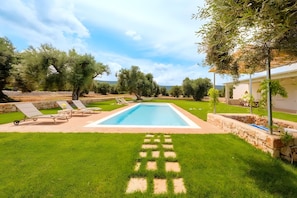A rectangular swimming pool with a stone border, surrounded by a well-maintained lawn and a few trees. - Apartment 'Oasis' with Private Terrace, Wi-Fi and Air Conditioning (Monopoli)