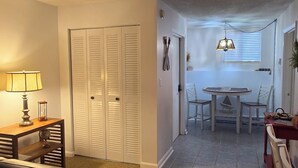 A living room with a couch, a table with a lamp, and a closed white closet. - Weirs beach retreat (Laconia)