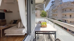 A balcony with a sofa, table, and potted plants. - S P ART Boutique Acropolis (Athina)