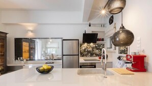A modern kitchen with a central island, stainless steel appliances, and a red espresso machine. - S P ART Boutique Acropolis (Athina)