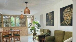 A spacious living area with a dining set, a sofa, and a large window with a view of greenery. - VFH The Sicilian Dream Pool Villa (Altavilla Milicia)