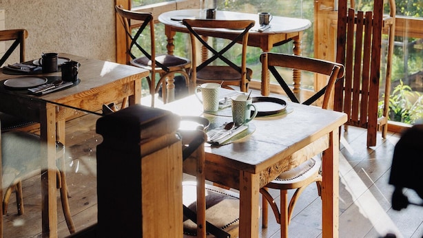 Een rustiek houten interieur met een eethoek, houten balken in het plafond en ingelijste foto's aan de muur.