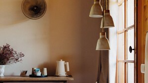 Een gezellige kamer met een bed, nachtkastje met lamp, een wandklok en een raam met gordijnen.