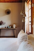 Una habitación acogedora con una cama, una mesita de noche con lámpara, un reloj de pared y una ventana con cortinas.