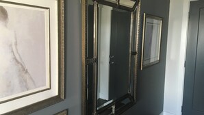 Ein Flur mit dunklen Wänden, gerahmten Kunstwerken und großen Spiegeln.