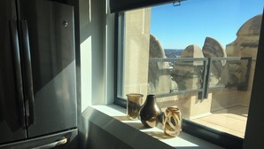 Eine Küche mit einem Kühlschrank, einem Fenster mit Blick auf die Stadt und drei Vasen auf der Fensterbank.