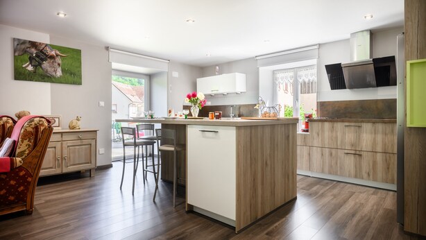 Una cocina moderna con una isla central, armarios de madera y un microondas integrado.