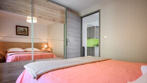 Un dormitorio con cama, mesita de noche, l ámpara, espejo y vistas a una zona de cocina.