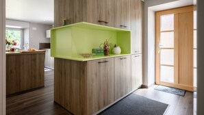 Una cocina moderna con armarios de madera, encimera verde y una puerta que da a una habitación luminosa.