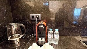 Une cuisine moderne dotée d’un plan de travail en granit, d’une machine à café, d’une bouilloire et de deux bouteilles d’eau.