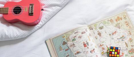 A bed with a pink ukulele, a Rubik's cube, and a travel-themed book.