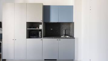 A modern kitchen with white and blue cabinets, a black countertop, and a stainless steel sink.