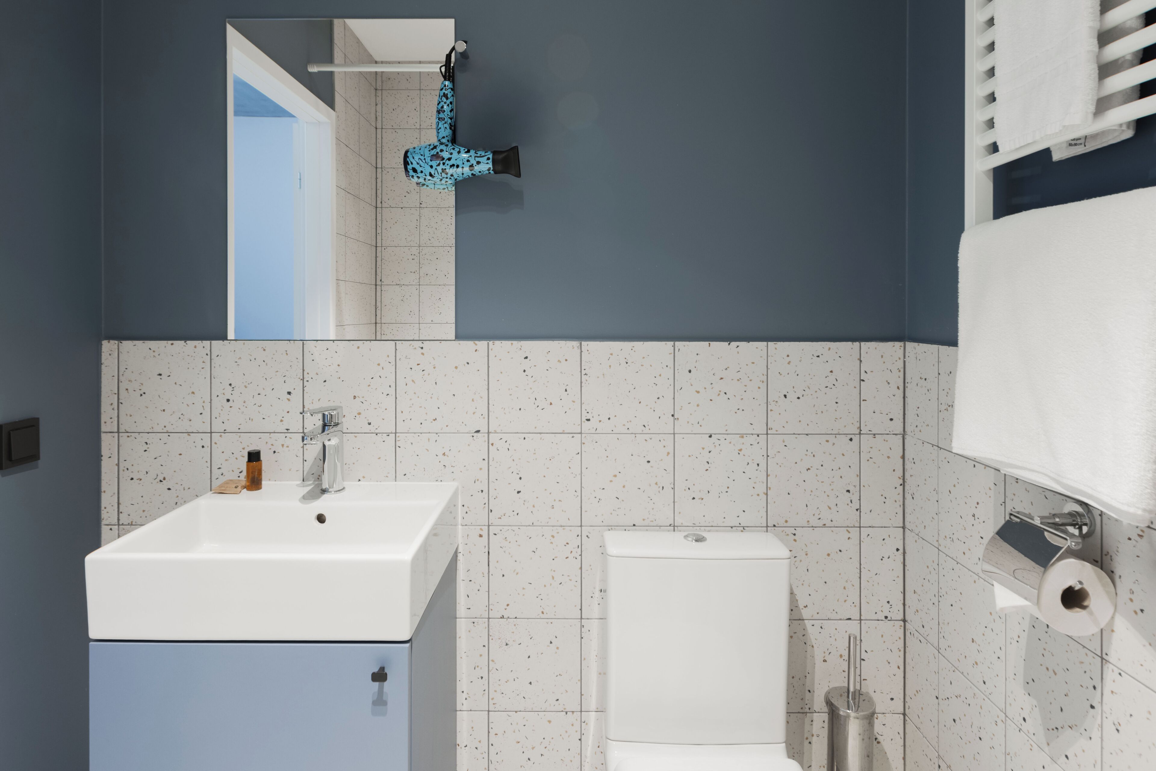 Un bagno con lavandino bianco, un water e uno specchio.