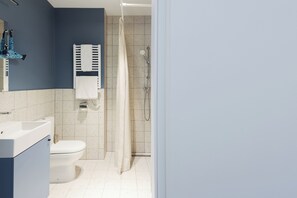 Ein Badezimmer mit Toilette, Waschbecken, Dusche und Handtuchhalter.