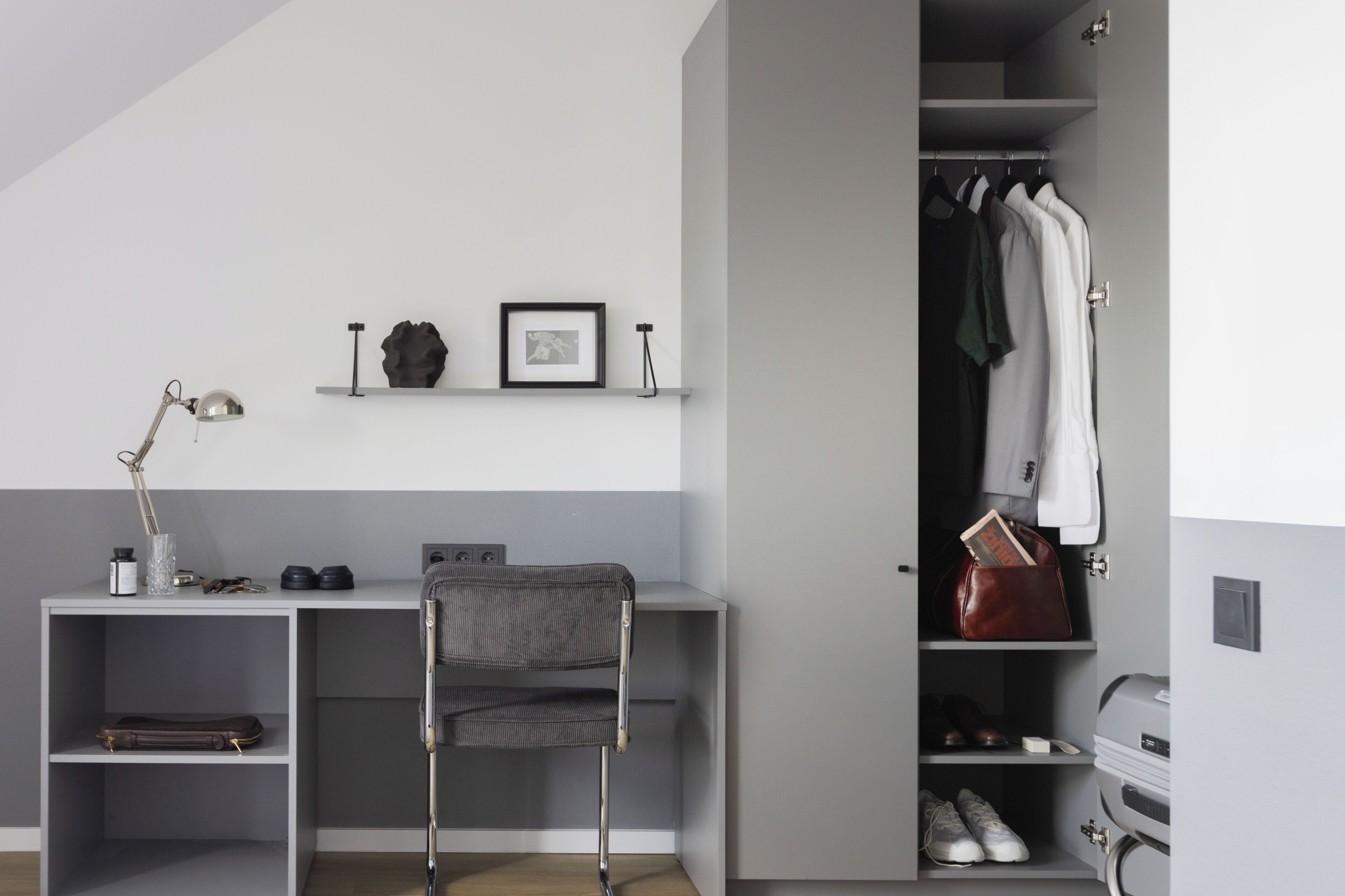 A room with a desk, chair, shelves, and a wardrobe.