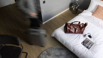 Una camera d'albergo con un letto, una valigia, una borsa e una rivista sul letto.