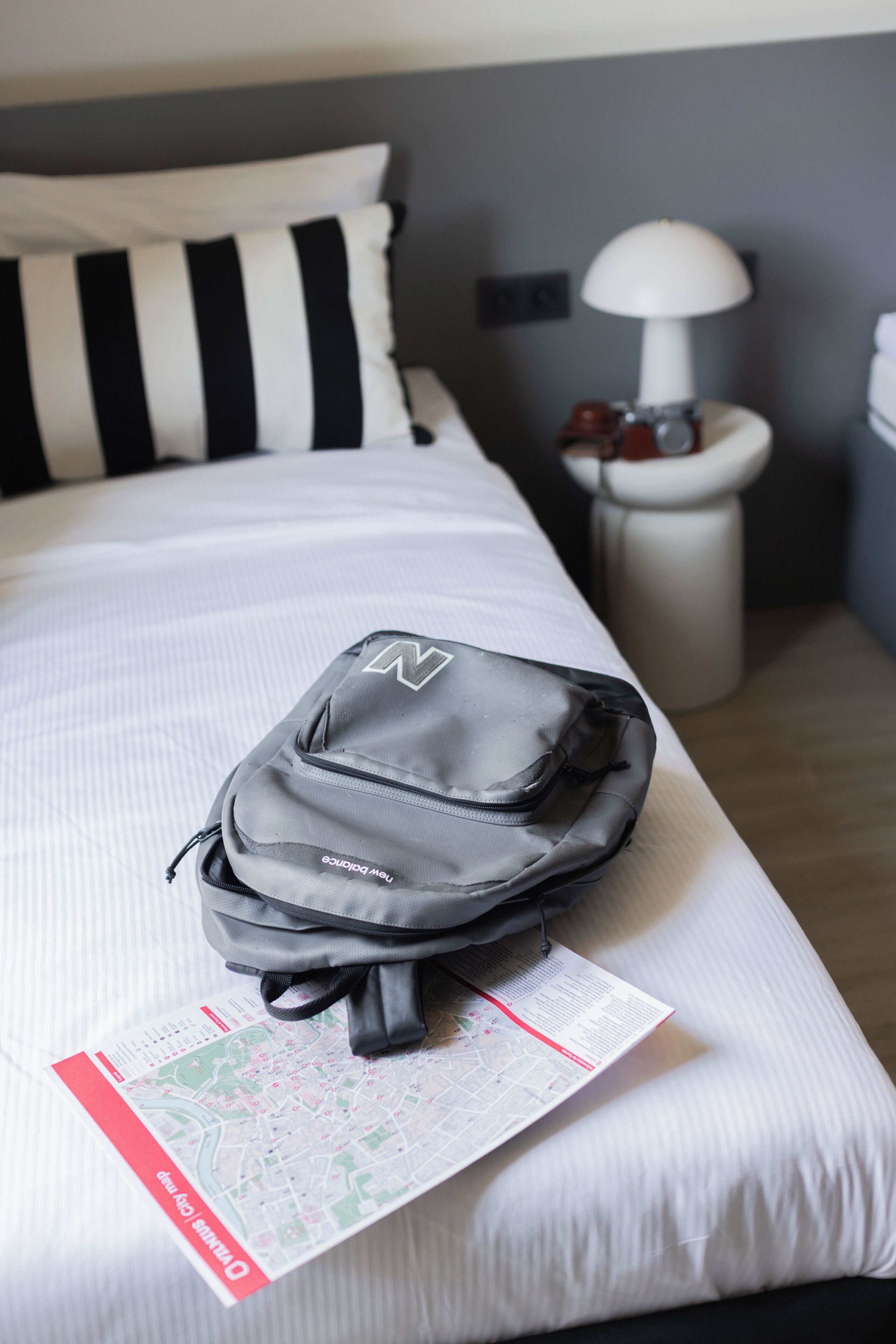 Una cama con una mochila negra y un mapa encima.