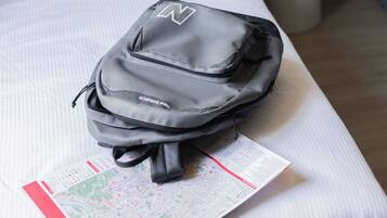 Una cama con una mochila negra y un mapa encima.