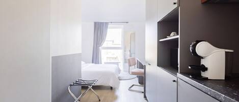 A modern hotel room with a bed, a desk, a chair, a desk lamp, and a mirror.