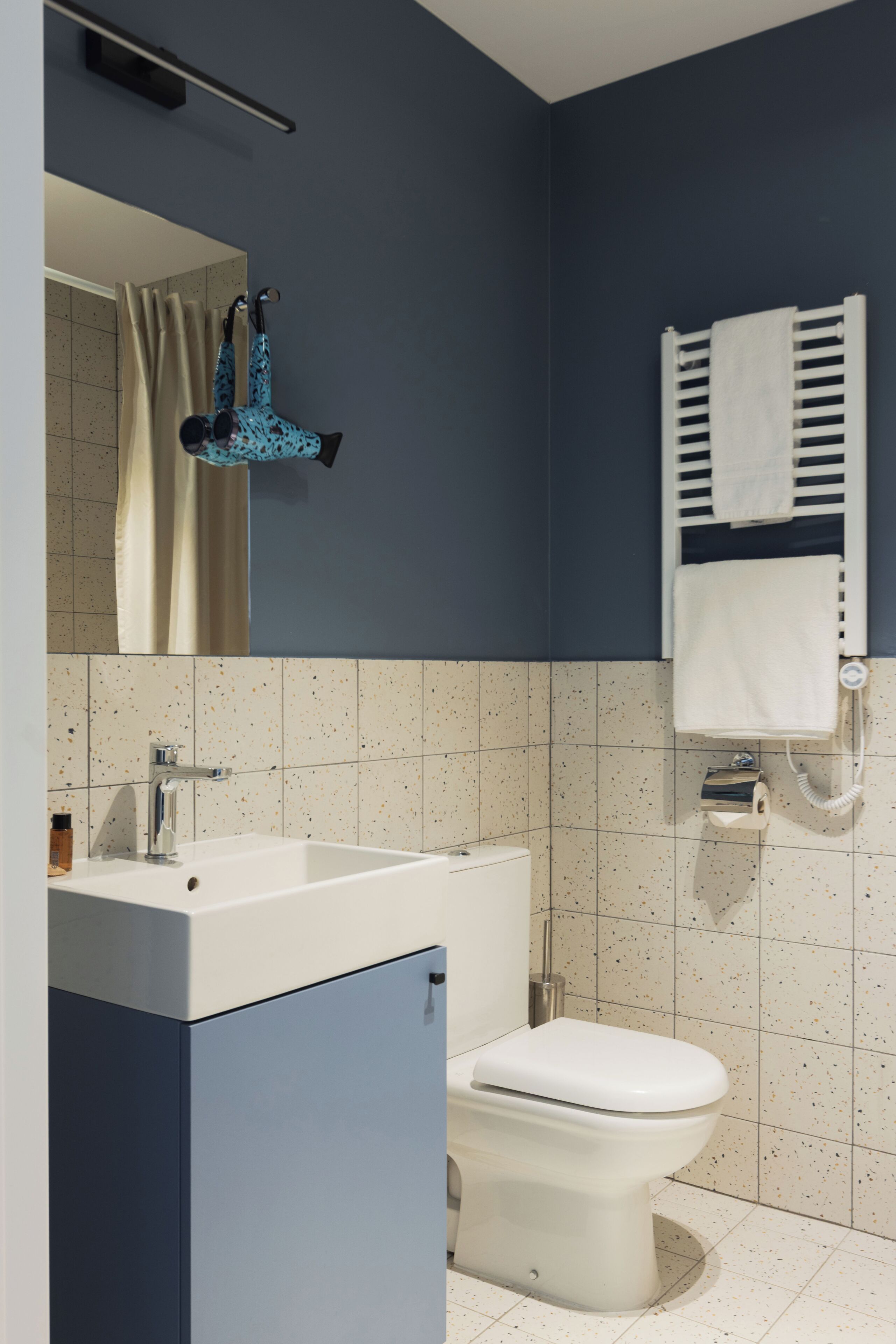 A bathroom with a white sink, a toilet, a towel rack with a white towel, and a mirror.
