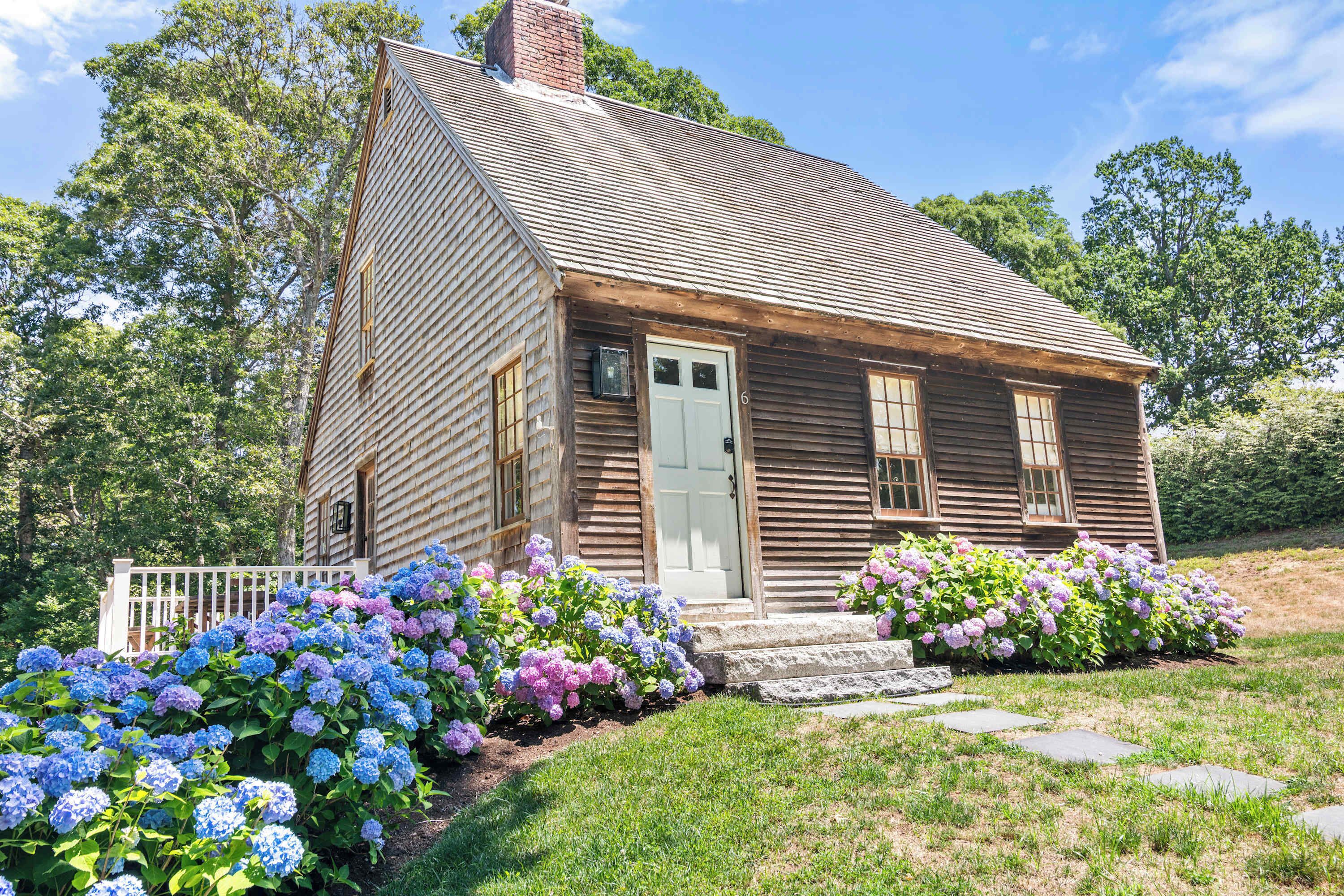 A rustic wooden house with a gabled roof, a front door, and a small porch.