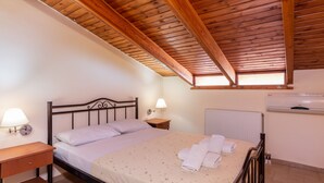 A bedroom with a wooden ceiling, a bed with a floral bedspread, two bedside lamps, a nightstand, and an air conditioning unit. - Villa Maria Apt 2 (Ligres)