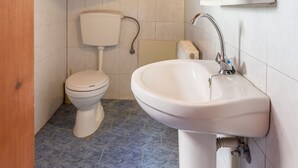 A small bathroom with a wooden ceiling, a toilet, a sink, and a mirror. - Villa Maria Apt 2 (Ligres)
