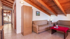 A cozy room with a wooden ceiling, a sofa, a table with a red tablecloth, and a painting on the wall. - Villa Maria Apt 2 (Ligres)