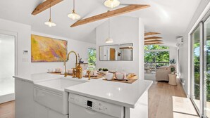 Una cocina moderna con una isla grande, luces colgantes y vistas al exterior.