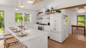 Una cocina moderna con armarios blancos, una isla central e iluminación colgante.