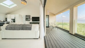 Un interior moderno con un sofá blanco, una zona de comedor y vistas al exterior.