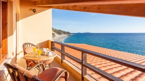 Un balcone con vista sul mare, un tavolo con bevande e sedie in vimini.