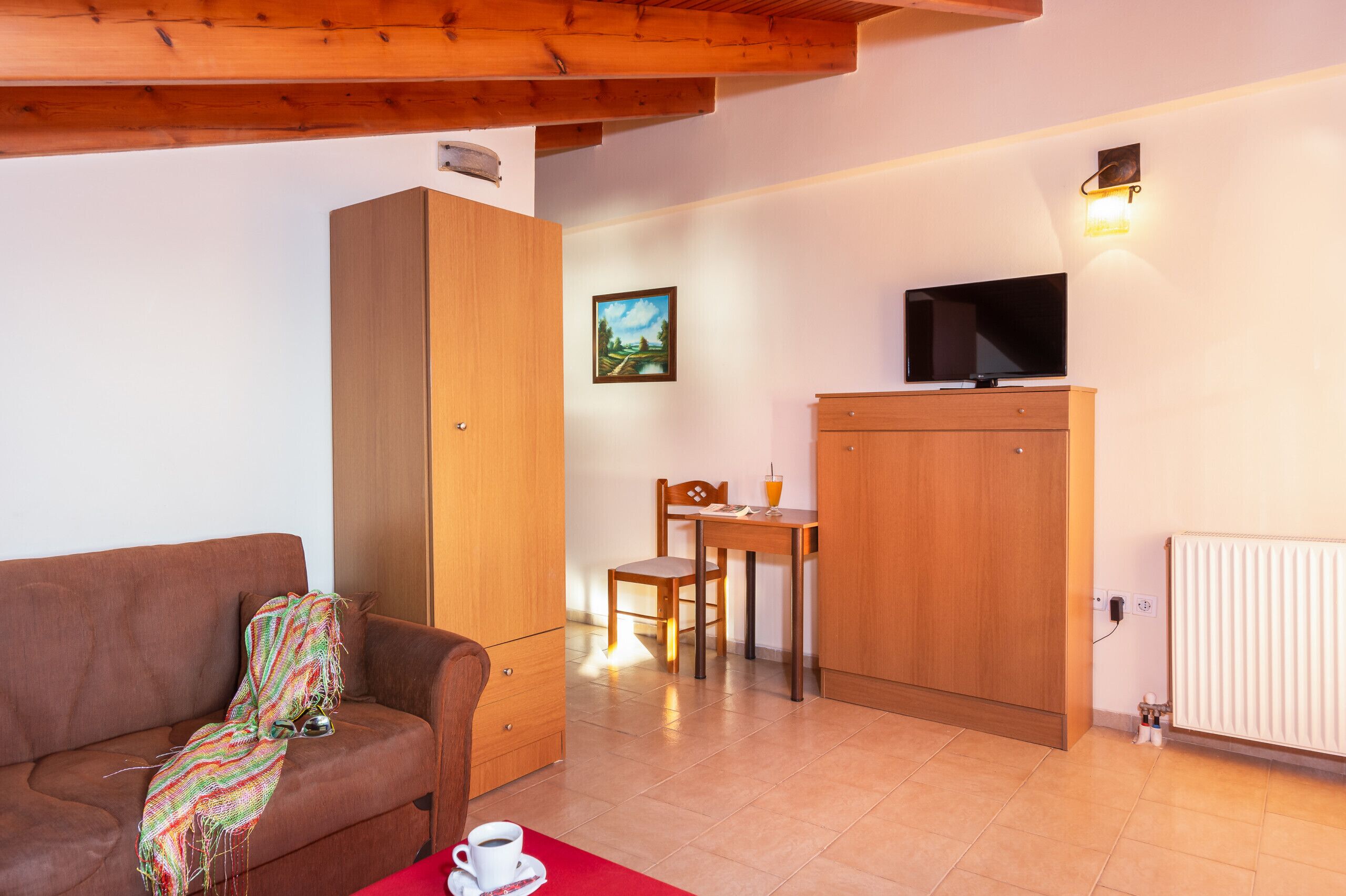Uma sala de estar aconchegante com um sofá marrom, um armário de madeira, uma televisão e um espaço de jantar com mesa e cadeiras.