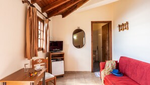 A cozy room with a wooden table, a red sofa, a TV, and a mirror on the wall. - Villa Maria Studio 4 (Ligres)
