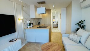 Ein modernes Wohnzimmer mit einem Flachbildfernseher, einem Holztisch, einem weißen Sofa und einem Deckenventilator.
