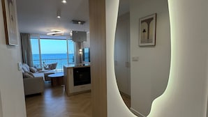 Ein modernes Wohnzimmer mit großem Spiegel, einer Couch, einer Essecke und Meerblick.
