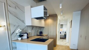 Eine moderne Küche mit Marmor-Spritzschutz, Holzschränken und einer Kochinsel.