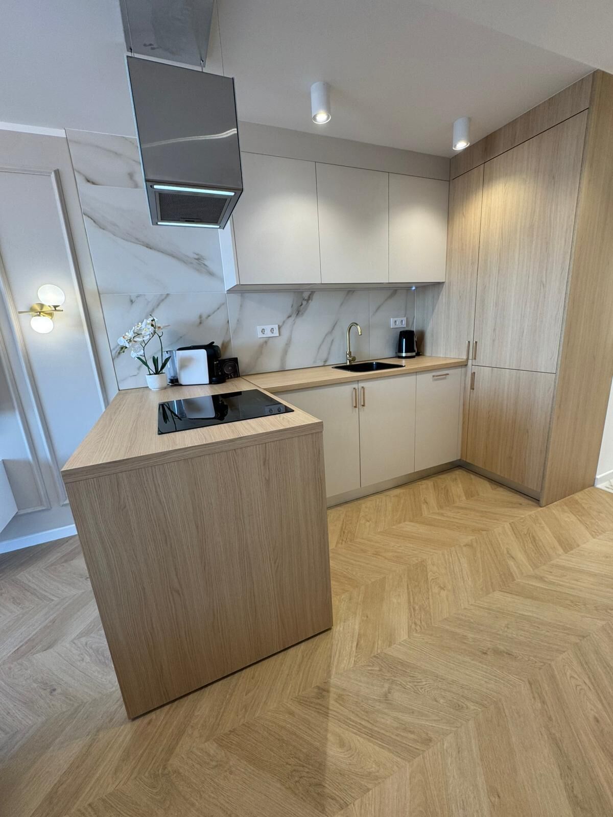 Una cocina moderna con una isla central, armarios de madera clara y salpicadero de mármol.
