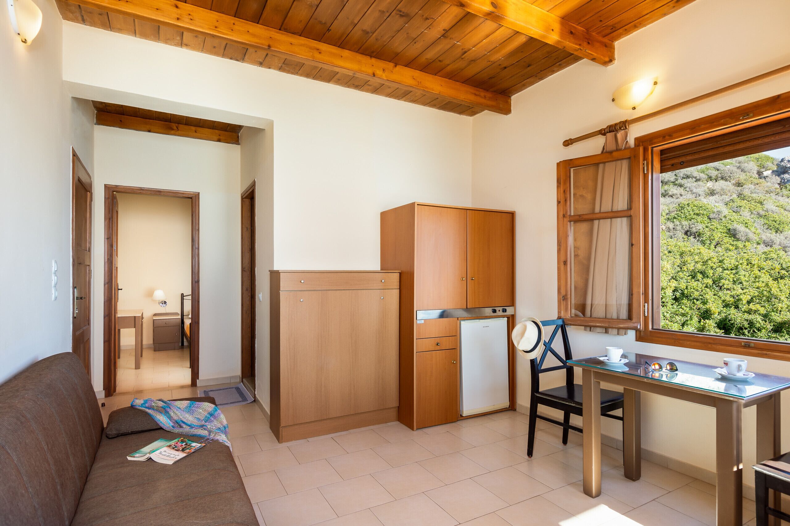 A compact kitchen with wooden cabinets, a refrigerator, and a dining table with chairs.