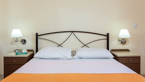 Una cama bien hecha con sábanas blancas y dos almohadas, flanqueada por mesitas de noche con lámparas y un libro.